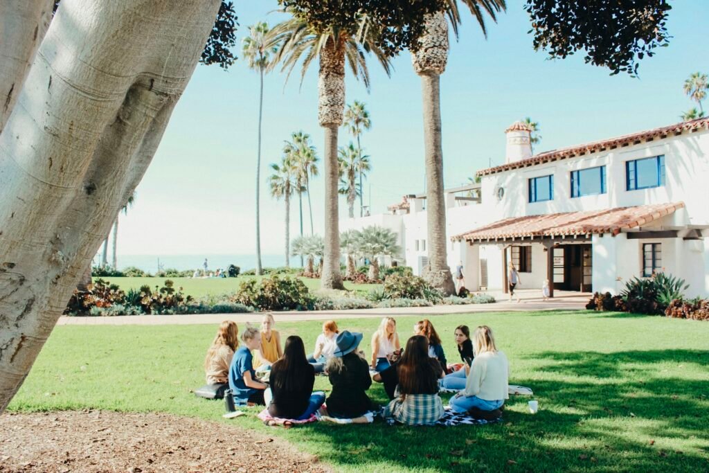 A small group sitting together in a circle on a sunny lawn
